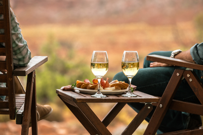 Ein Paar sitzt auf Holzstühlen bei einem Glas Wein.