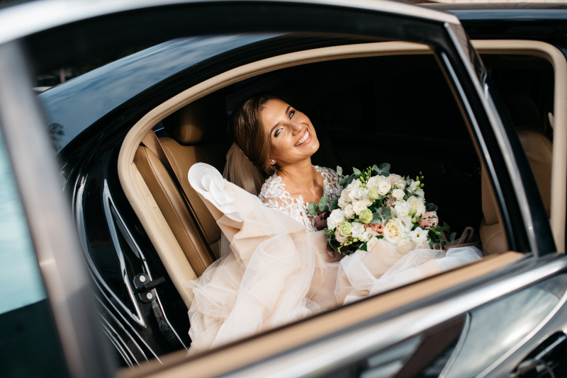 Eine strahlende Braut steigt ins Auto