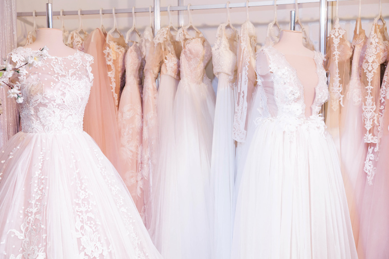 Verschiedene Brautkleider auf Kleiderhaken in einem Laden.